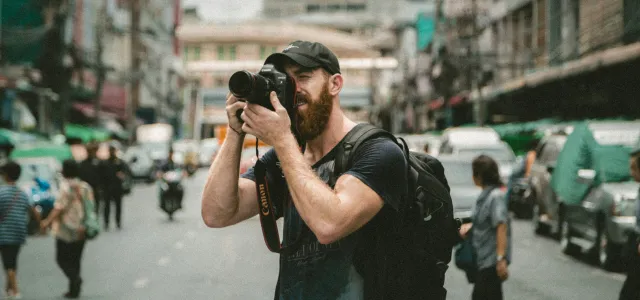 shallow focus photography of man using a DSLR camera by Jakob Owens courtesy of Unsplash.